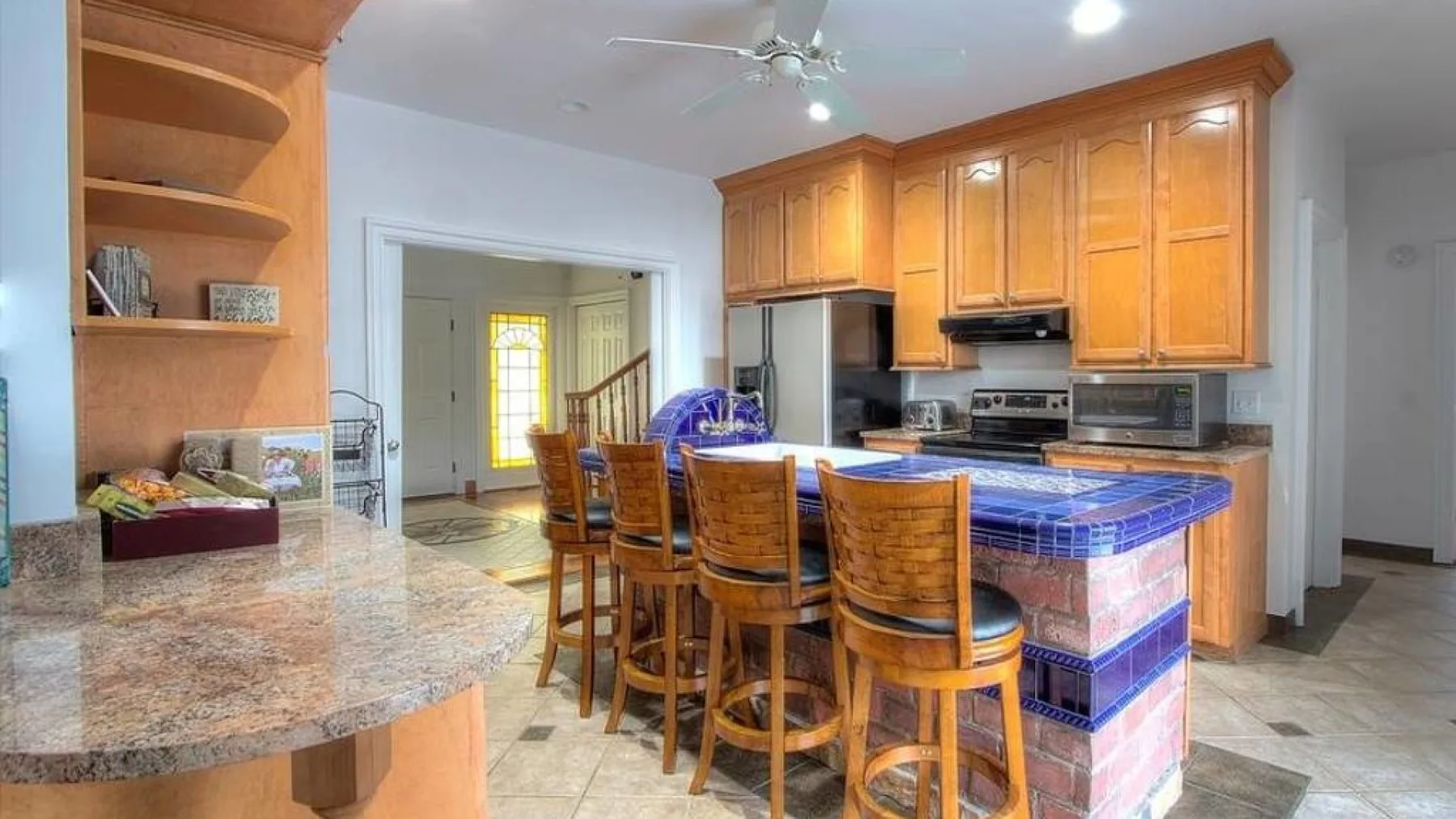 A kitchen and dining area with a blue-tiled island and wooden cabinets.
