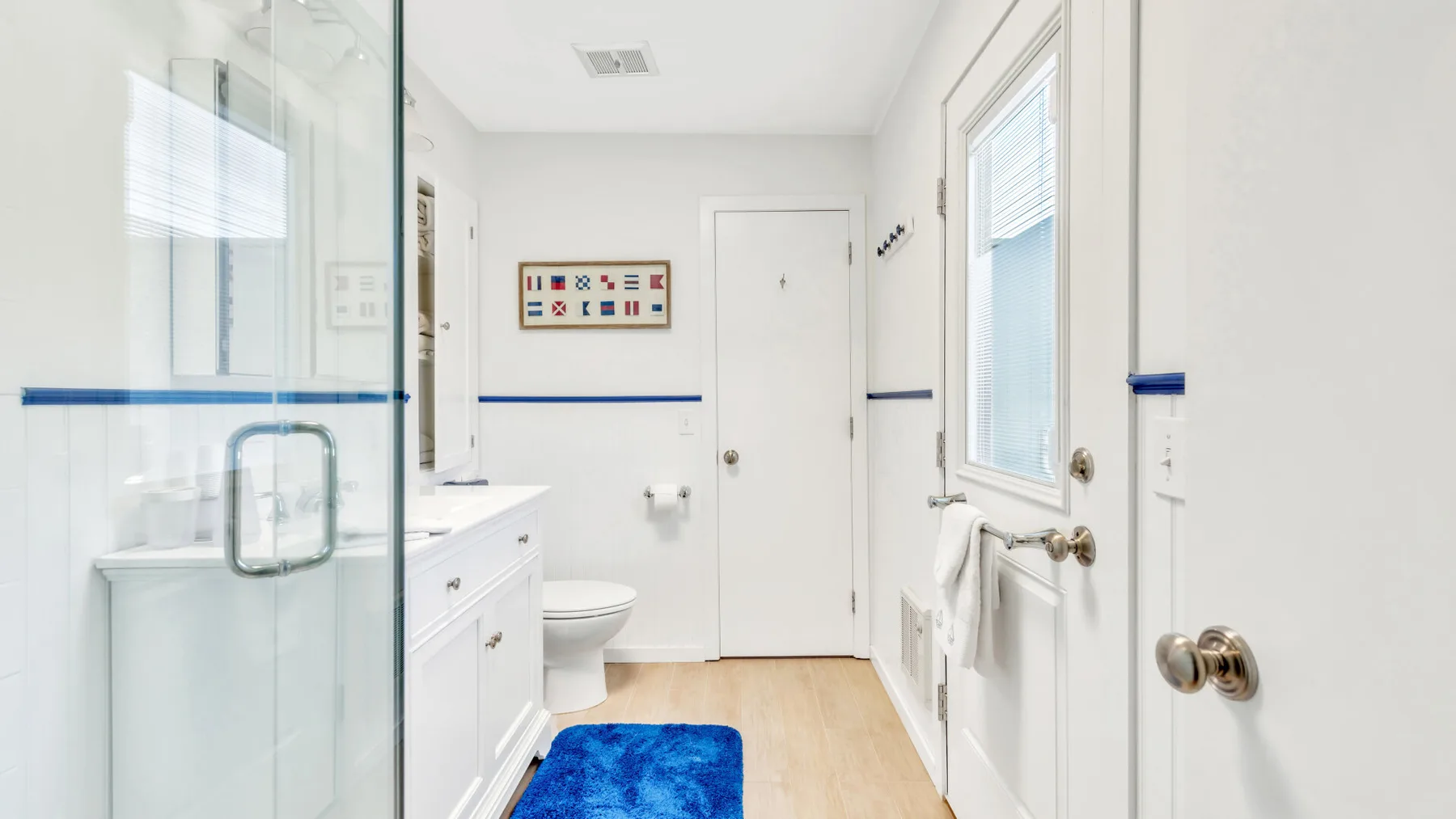 Un baño luminoso con ducha de vidrio, lavabo y sanitario.