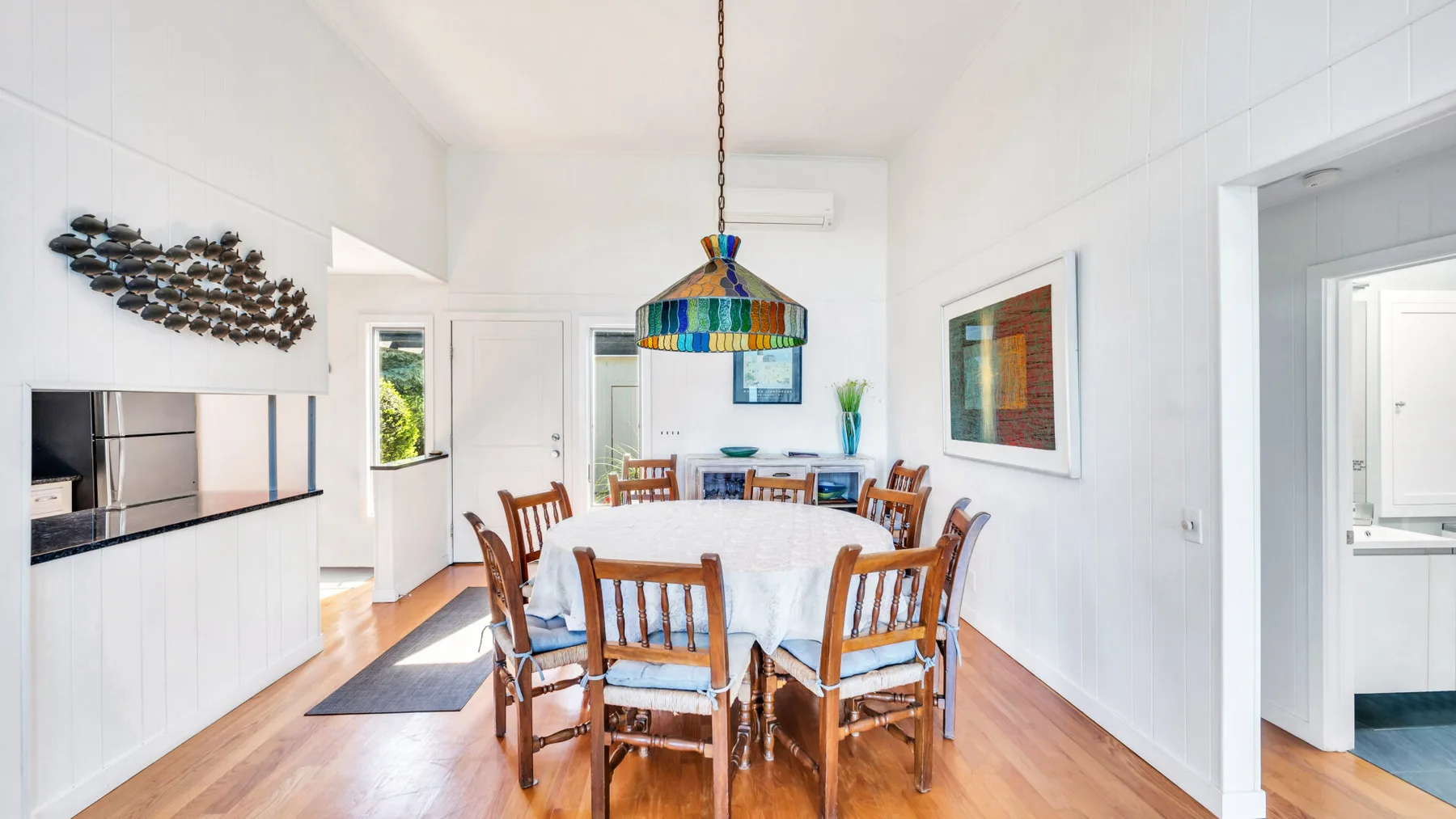 Un comedor luminoso con una mesa grande rodeada de asientos de madera.