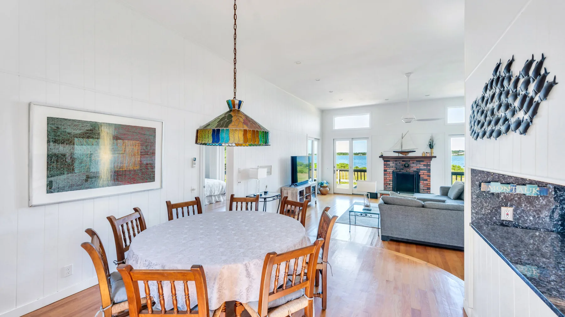 Una luminosa zona de comedor y sala de estar con una mesa larga y asientos junto a las ventanas.