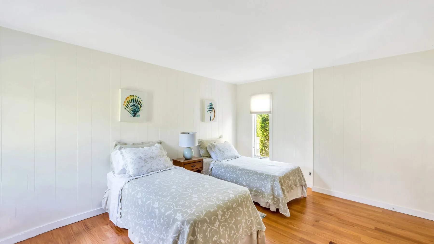 Un dormitorio luminoso con dos camas y ropa de cama blanca.