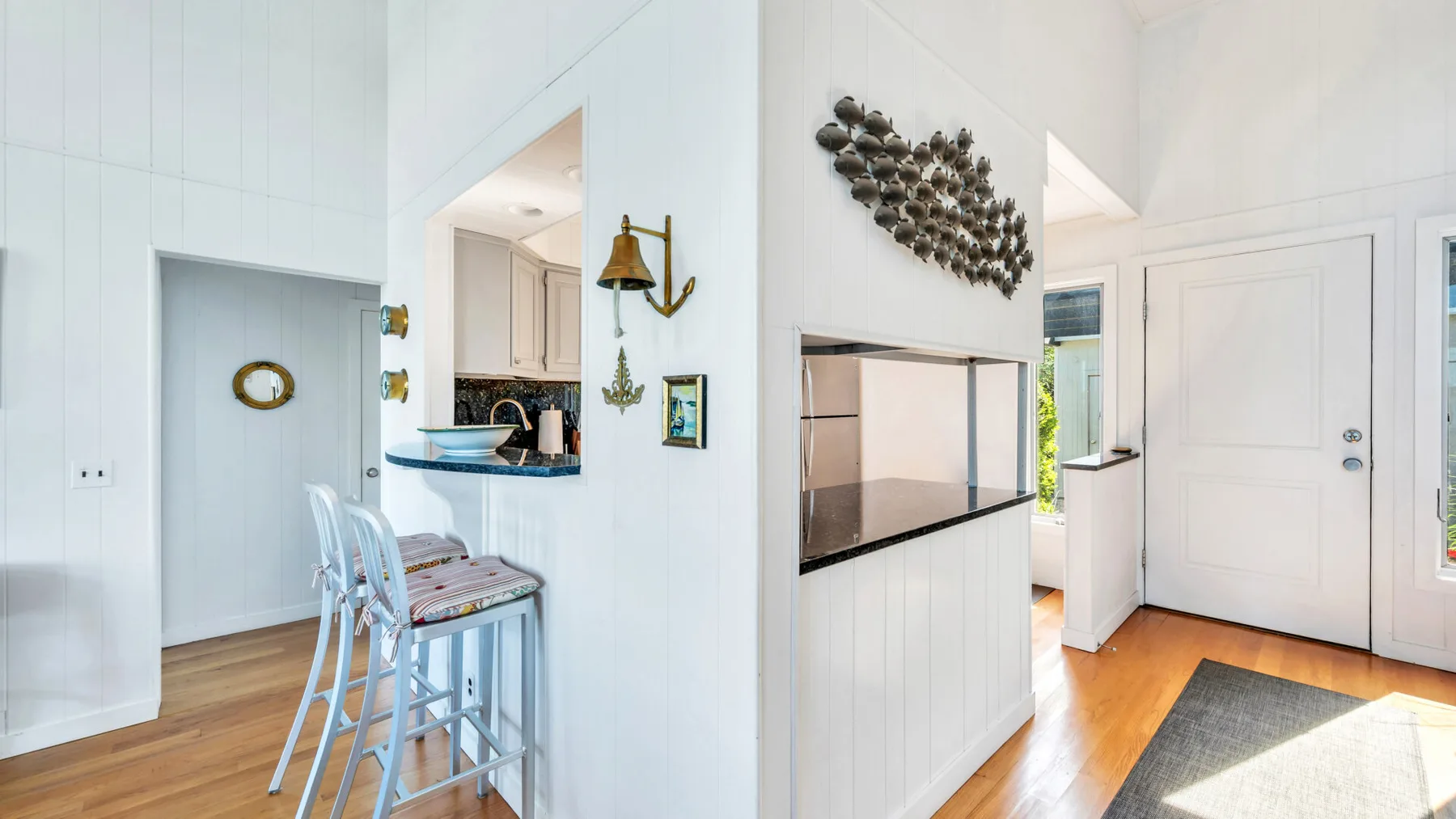 Una cocina y comedor luminosos con una barra de desayuno y gabinetes blancos.
