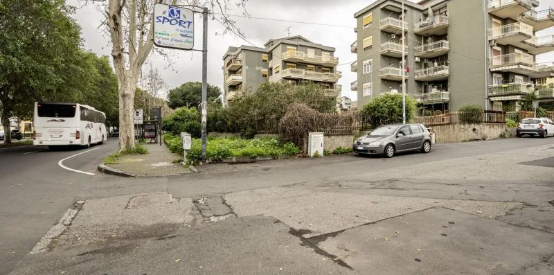 Una intersección urbana con edificios de apartamentos, coches estacionados y árboles junto a la calle.