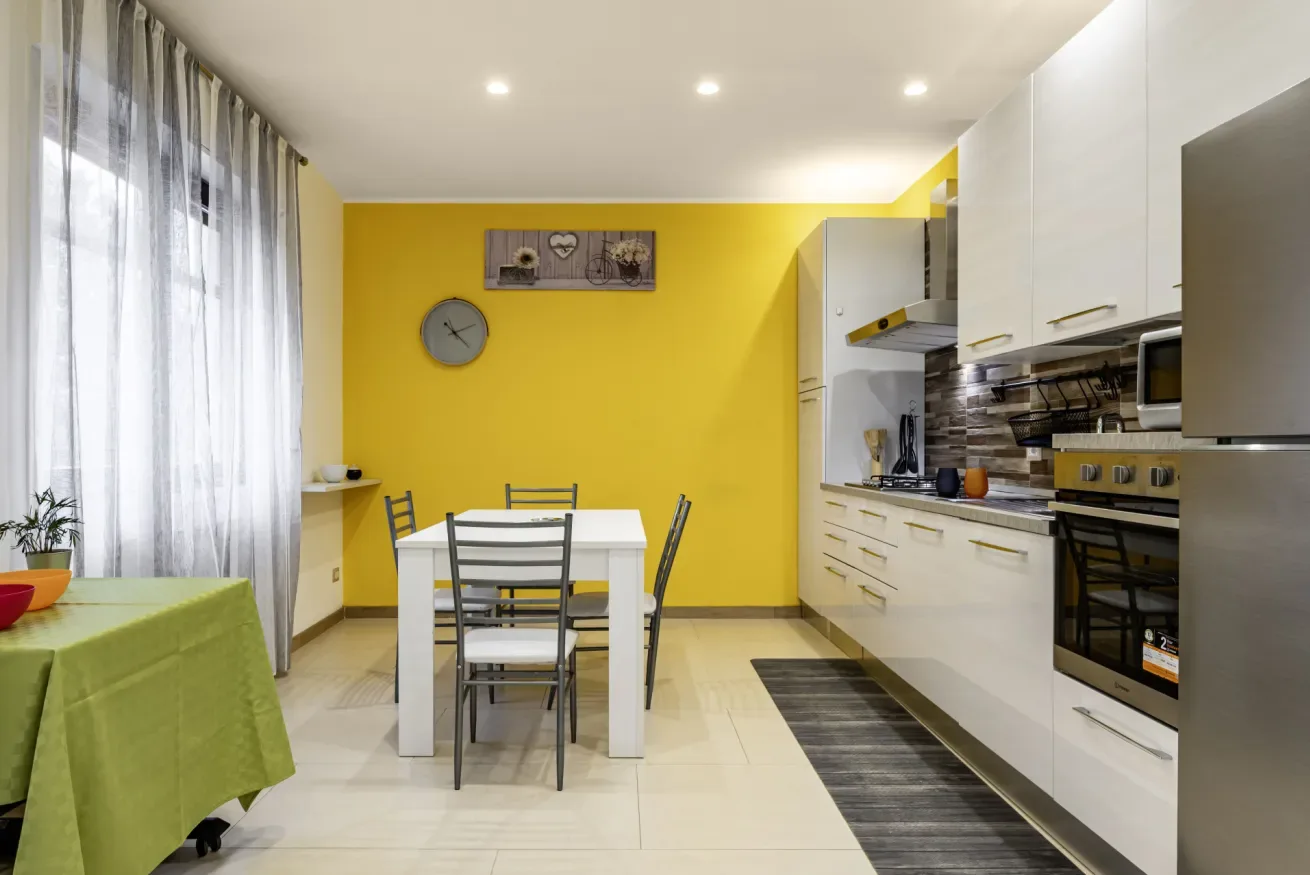Una cocina y comedor luminosos con una mesa junto a paredes amarillas.