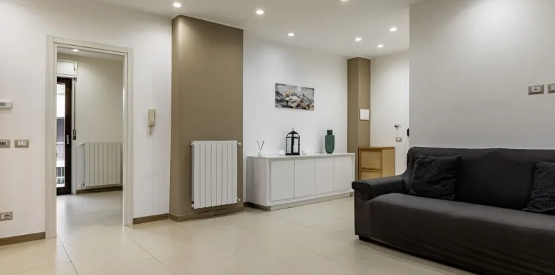 A living room with dark seating, a low cabinet, and a radiator.