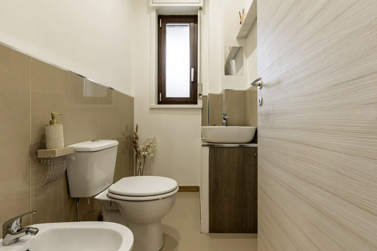 Un baño con inodoro, lavabo y una ventana pequeña.