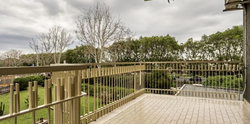 A tiled outdoor balcony overlooks trees and a grassy area.
