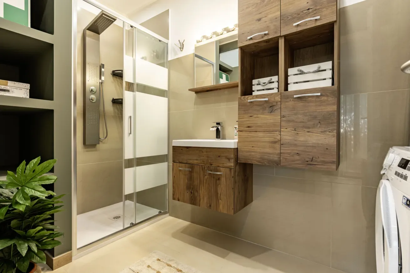 Un baño con ducha de vidrio, lavabo y armarios de acabado de madera.