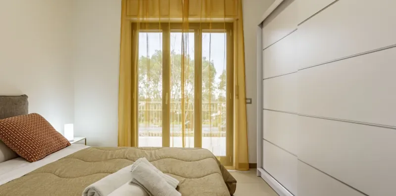 Un dormitorio con una cama junto a una ventana grande con cortinas doradas.