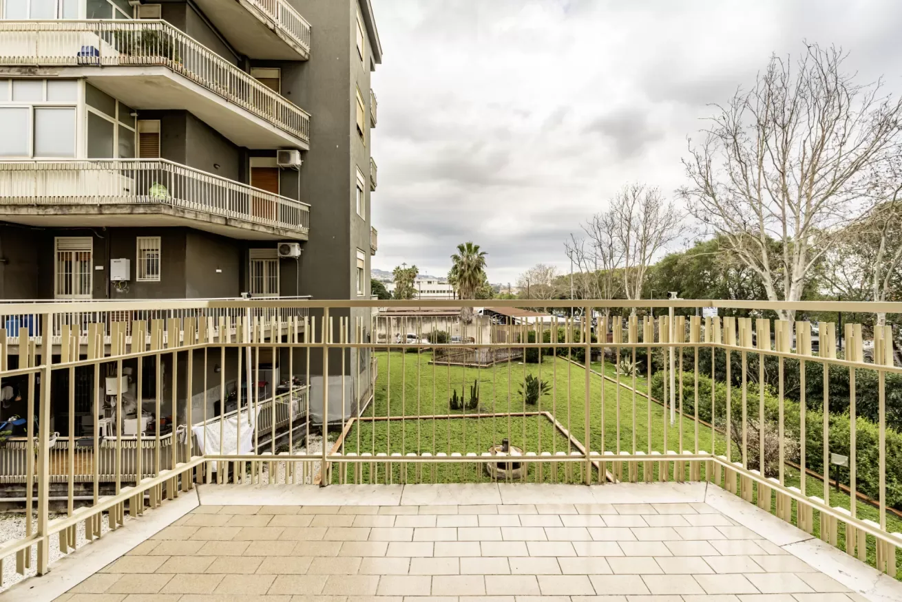 Una terraza pavimentada da a un patio con césped junto a un edificio residencial.