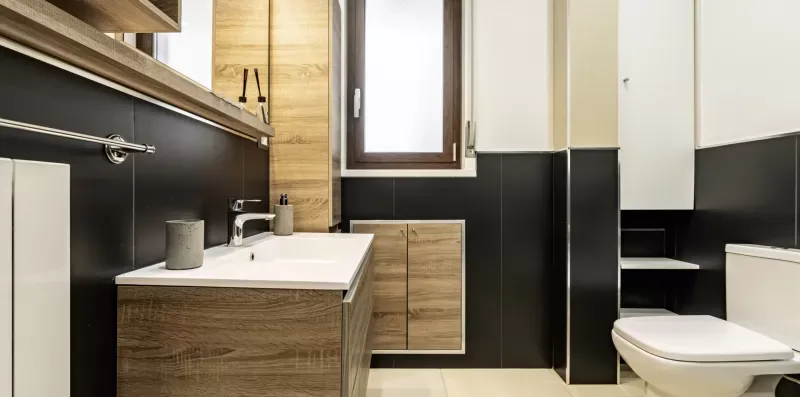 Un baño con lavabo, mueble con acabado de madera e inodoro.