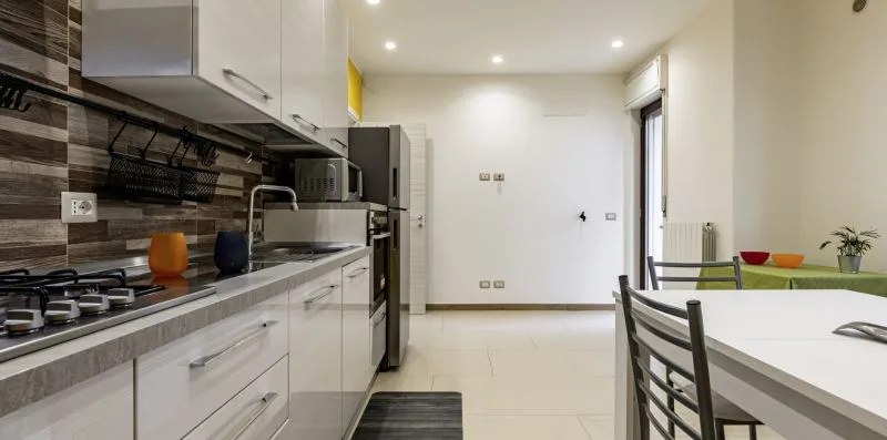 Una cocina moderna se abre a un comedor con una mesa blanca y sillas.