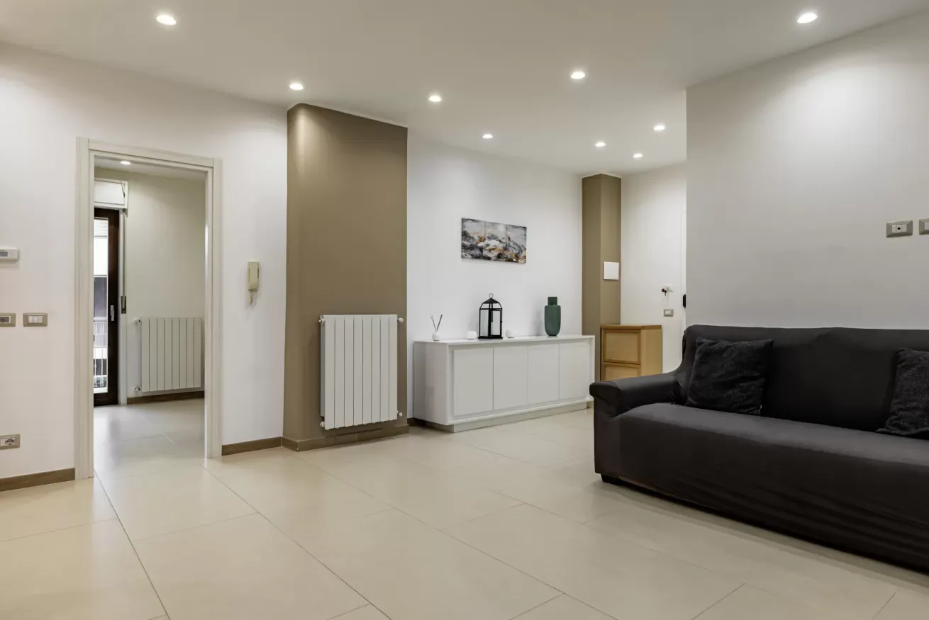 Una sala luminosa con asientos oscuros y un mueble blanco.