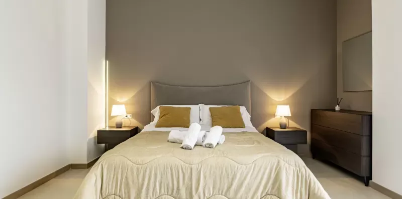 Un dormitorio con una cama bien tendida y mesitas de noche a juego.