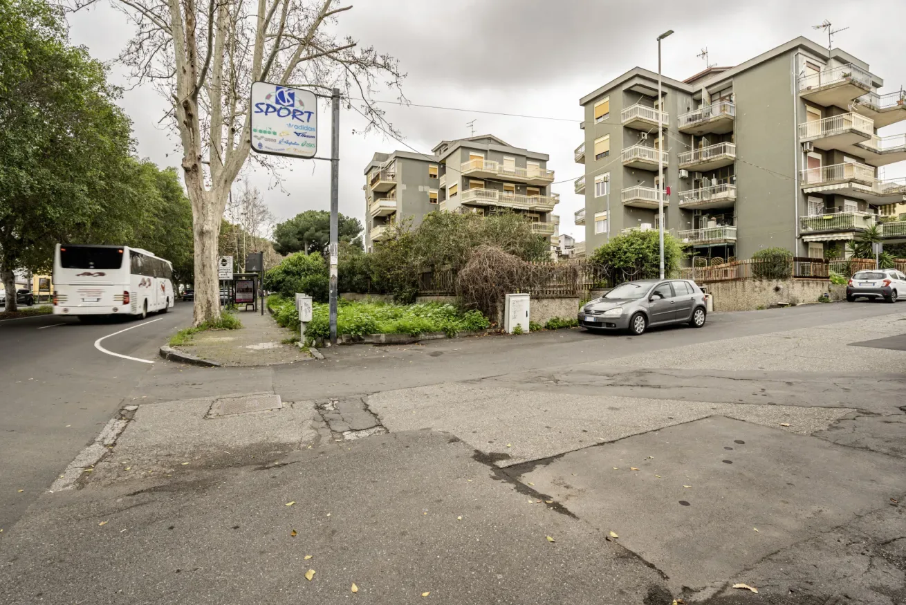Edificios de apartamentos se alzan detrás de una franja ajardinada en una intersección.