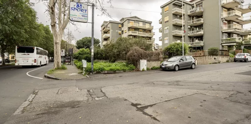 Una esquina urbana con edificios de apartamentos, coches estacionados y un autobús.