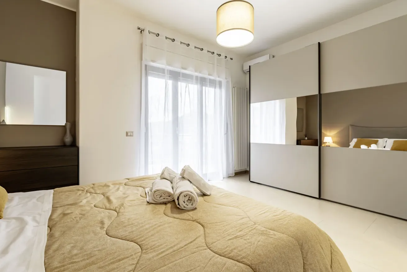 Un dormitorio con una cama, una cómoda y un gran armario con espejos.