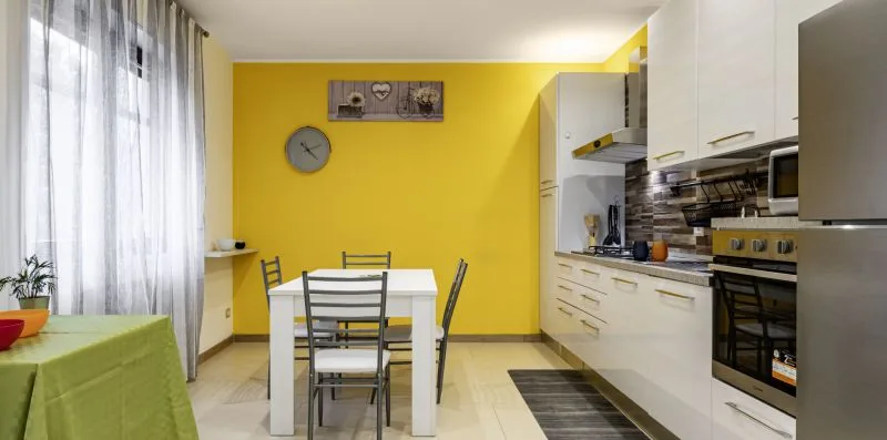 Una cocina y comedor luminosos con una mesa junto a los armarios blancos.