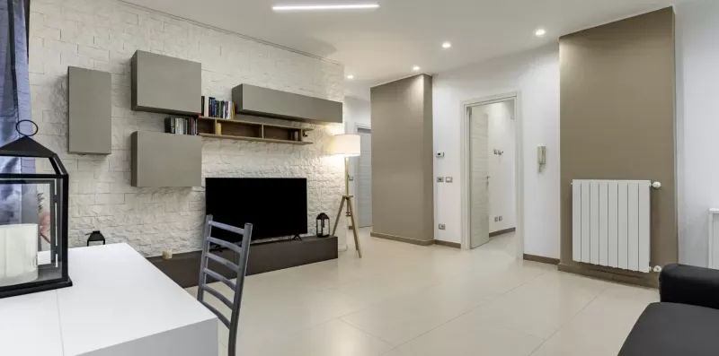 Una sala de estar moderna con televisor, armarios de pared y un radiador.