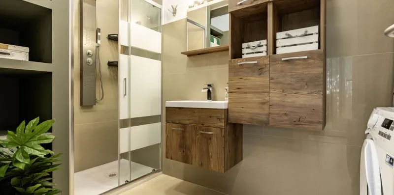 Un baño moderno con ducha de vidrio, lavabo y almacenamiento en la pared.