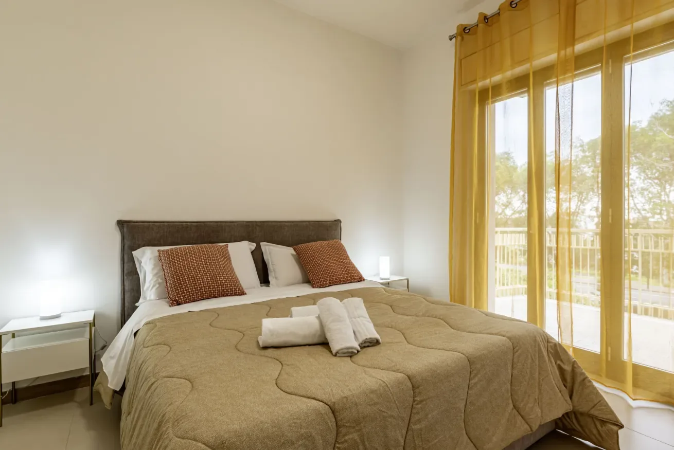 Un dormitorio con una cama y cortinas amarillas junto a puertas de vidrio.