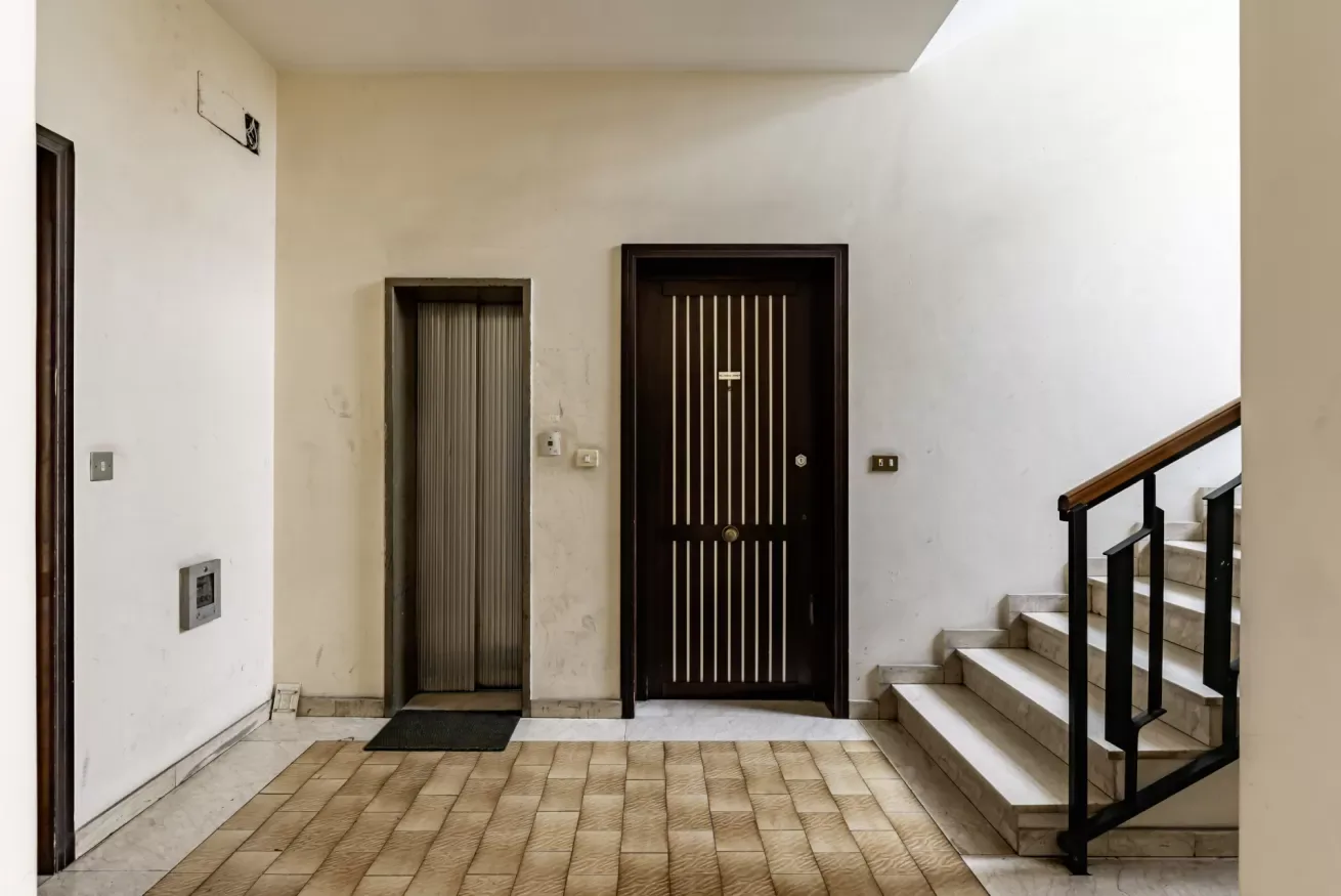 Una entrada interior con una puerta oscura y escaleras.