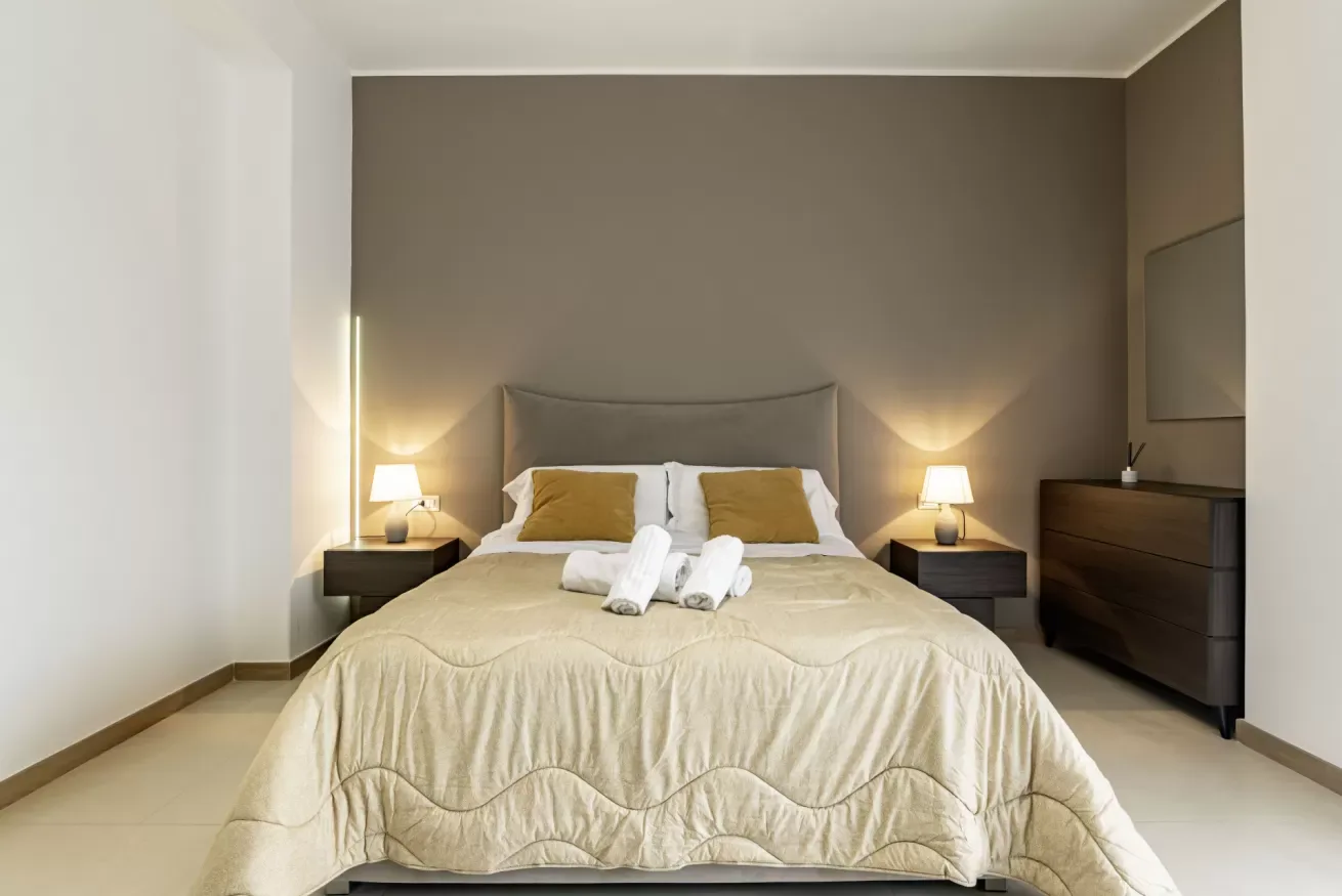Un dormitorio con una cama grande, mesitas de noche e iluminación cálida.