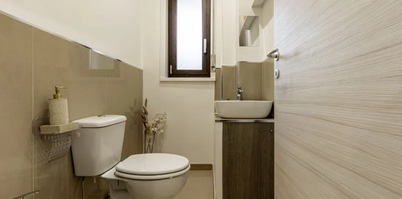 Un baño pequeño con inodoro, lavabo y una ventana estrecha.