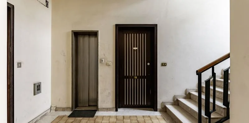 Un recibidor interior con una puerta oscura y escaleras.