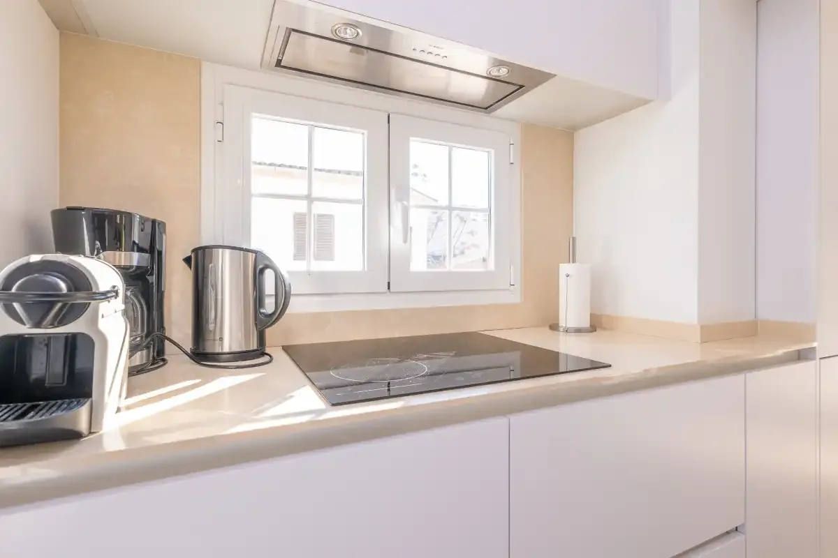 A bright kitchen counter with a stovetop beneath a window.