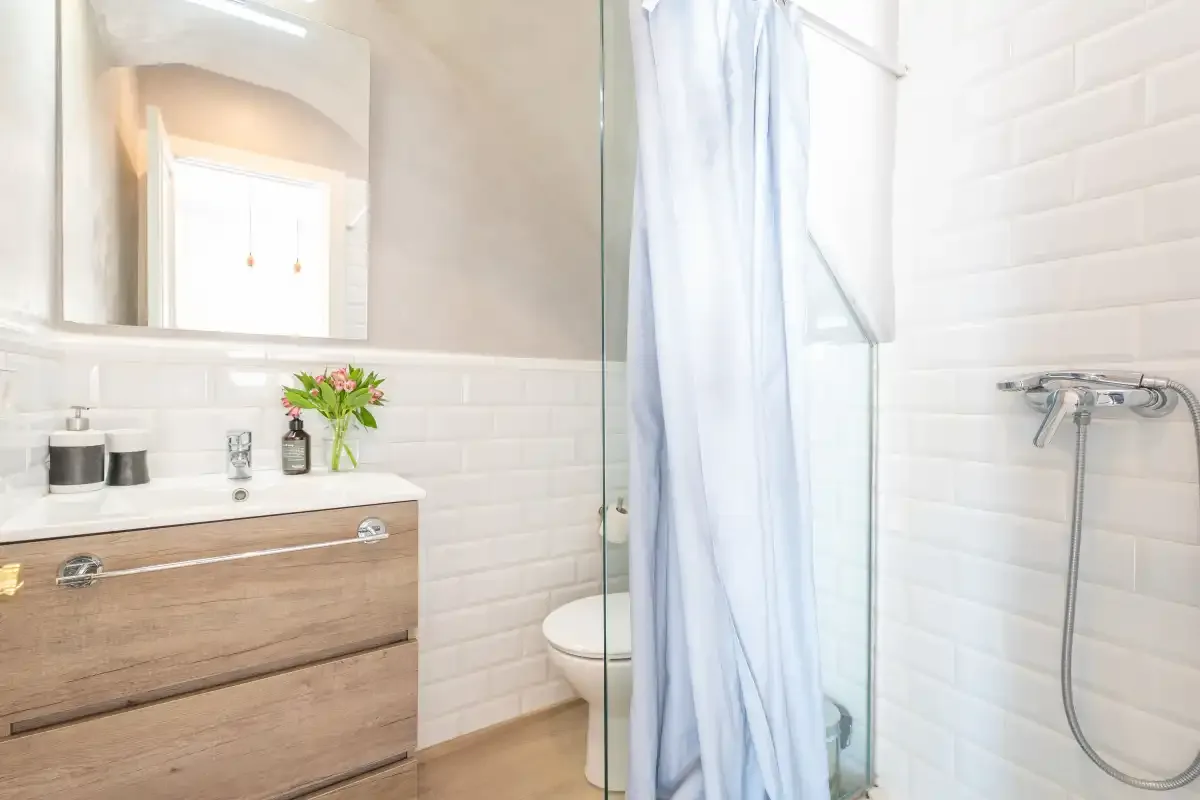 A bright bathroom with a wood-toned vanity, sink, and shower curtain.