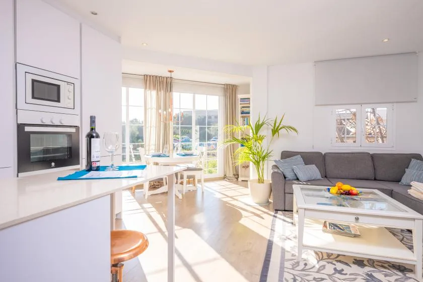 A bright open-plan living room and kitchen with a dining table and seating.
