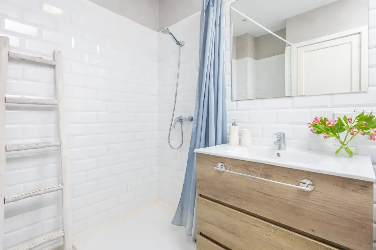 A bright bathroom with a shower, vanity, and large mirror.