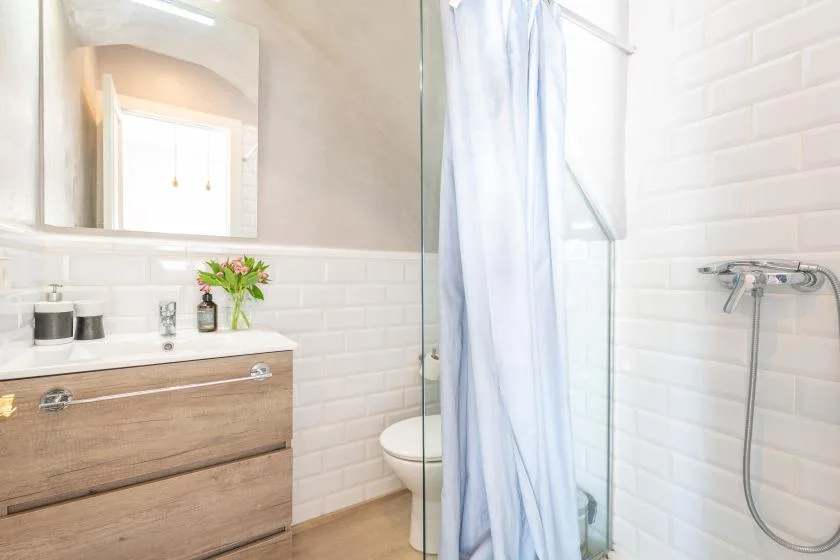 A bright bathroom with a wood vanity, mirror, and shower curtain.