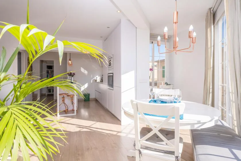 A bright dining area with a white table beside large windows.