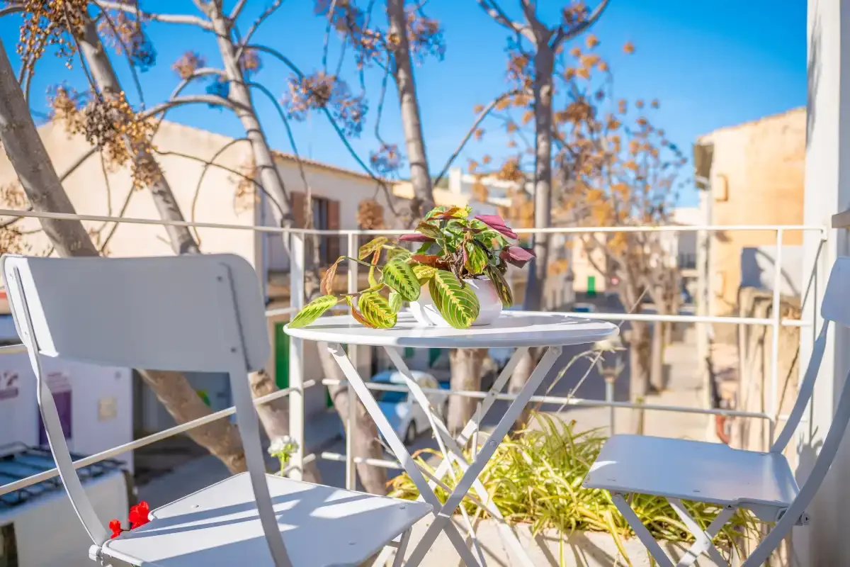 An outdoor terrace with a small table, seating, and potted greenery.