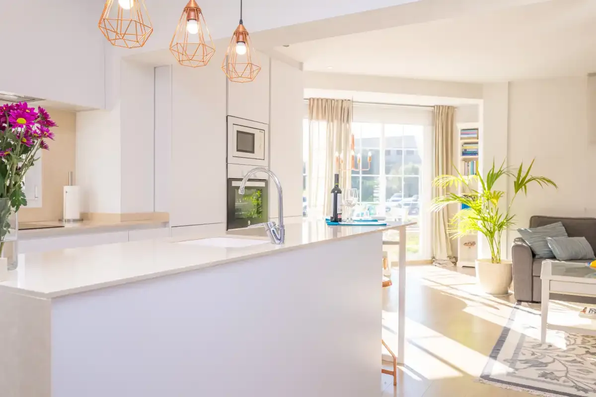 A bright open-plan kitchen and living area with large windows and a countertop.