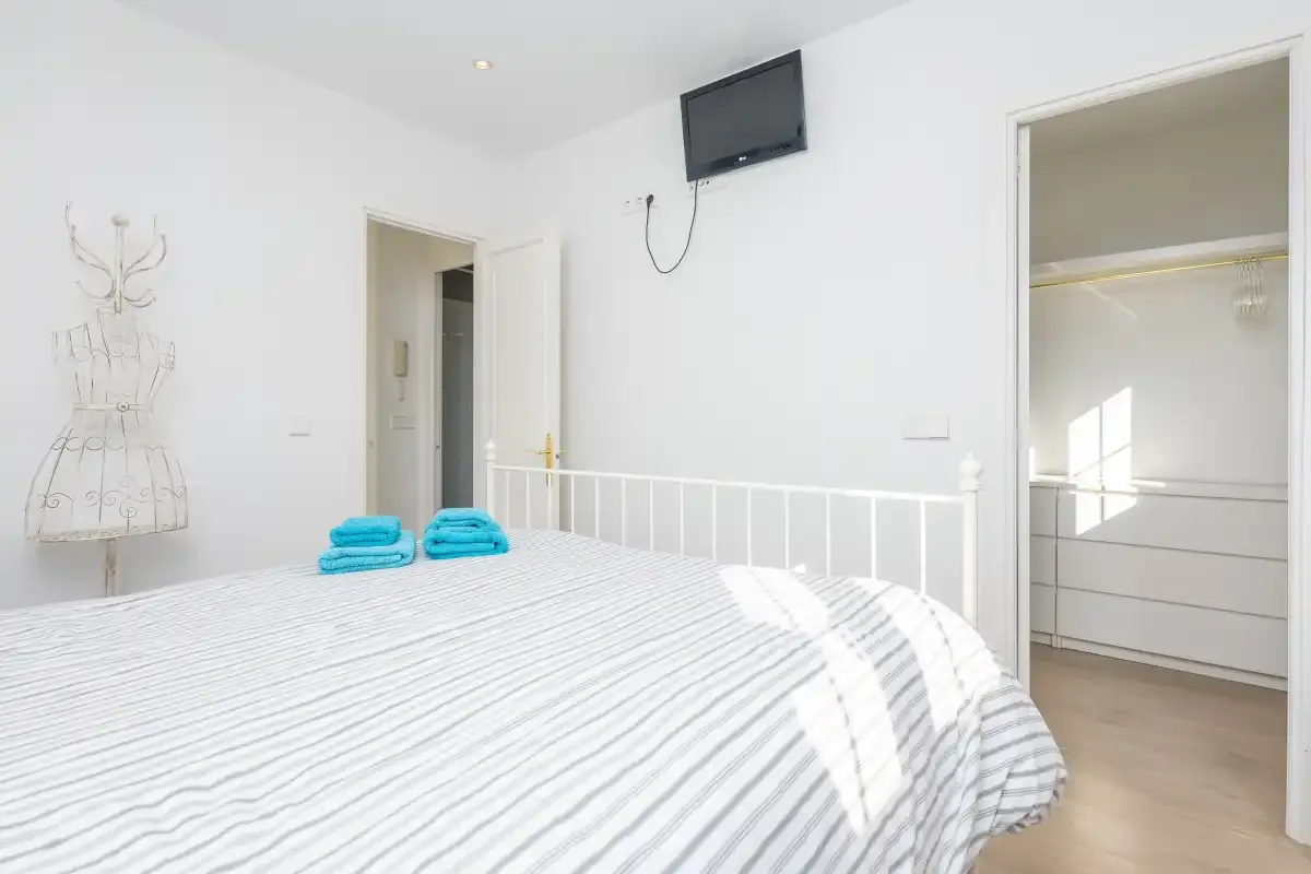 A bright bedroom with a striped bedspread and an open closet.