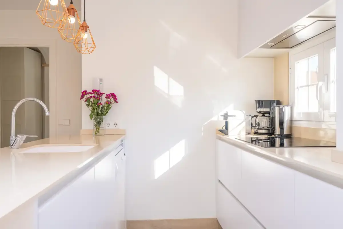 A bright white kitchen with a counter, sink, and cooking area.