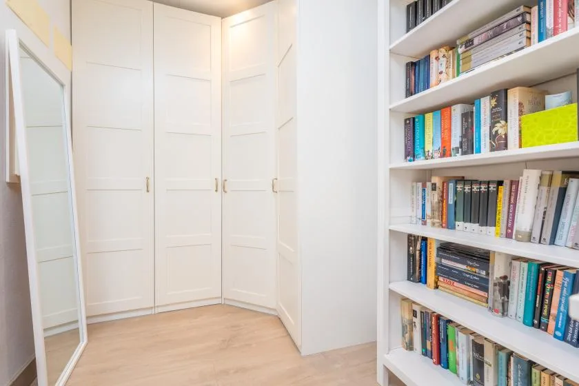 A bright room corner with white paneled doors and a full bookshelf.