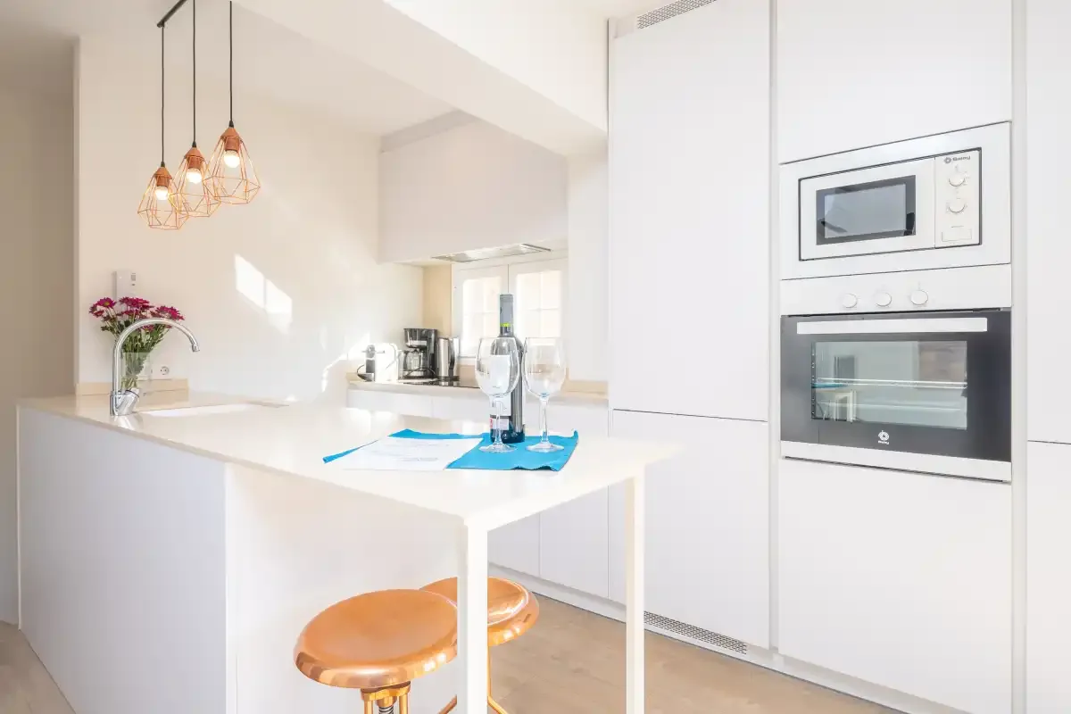 A bright kitchen with a white island and built-in appliances.