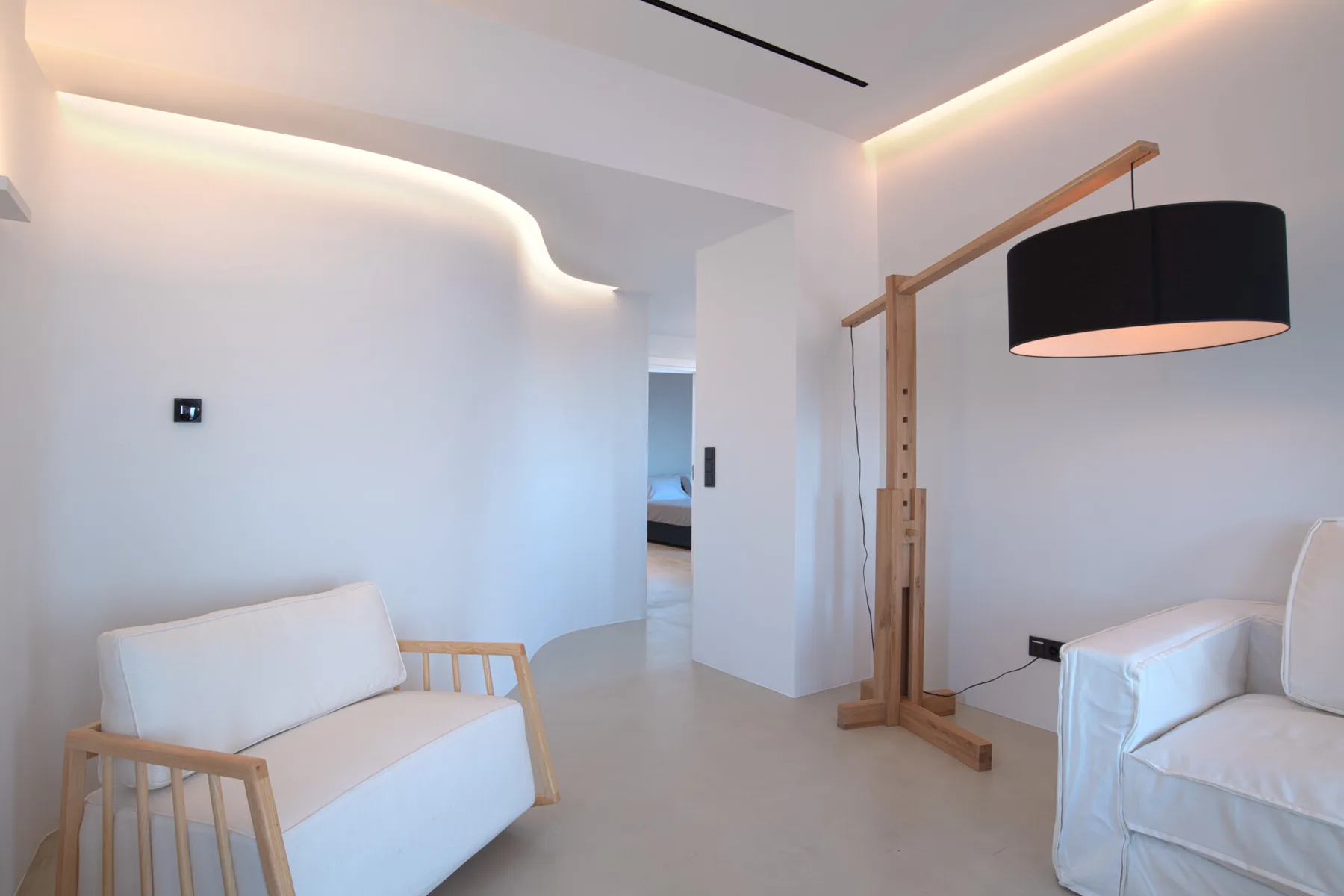 Una sala luminosa con asientos blancos y una lámpara de pie.