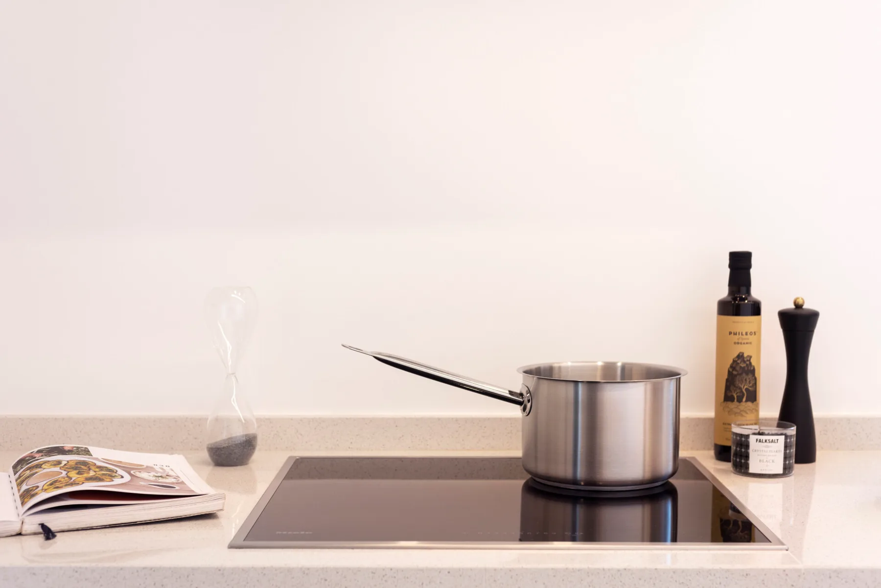 A kitchen cooktop with a stainless-steel pot and countertop condiments.