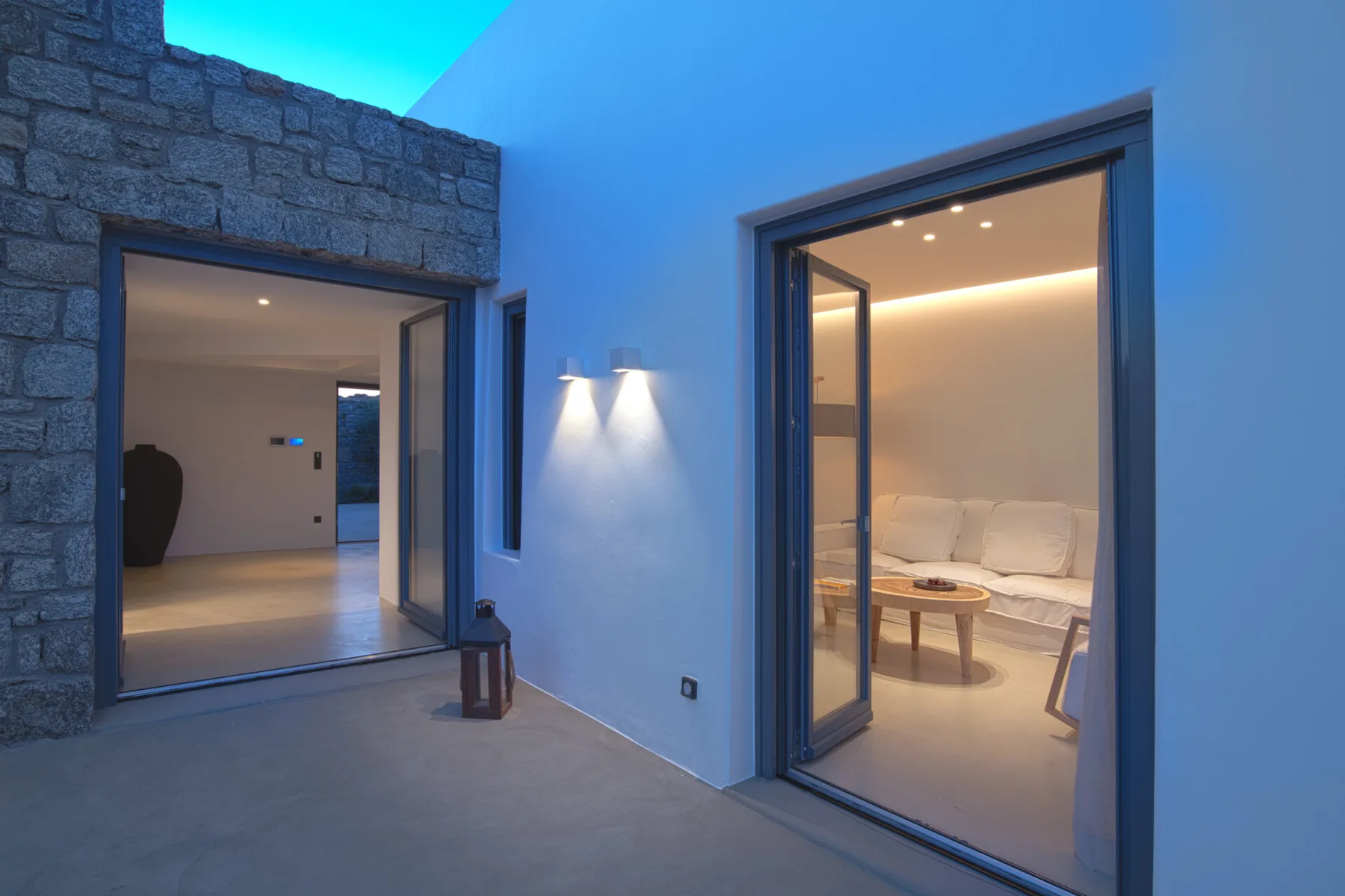 A modern patio opens onto a bright interior lounge with seating.