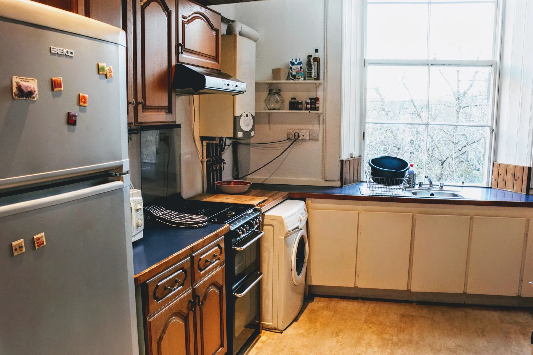 Una cocina con refrigerador, estufa y fregadero junto a una ventana grande.