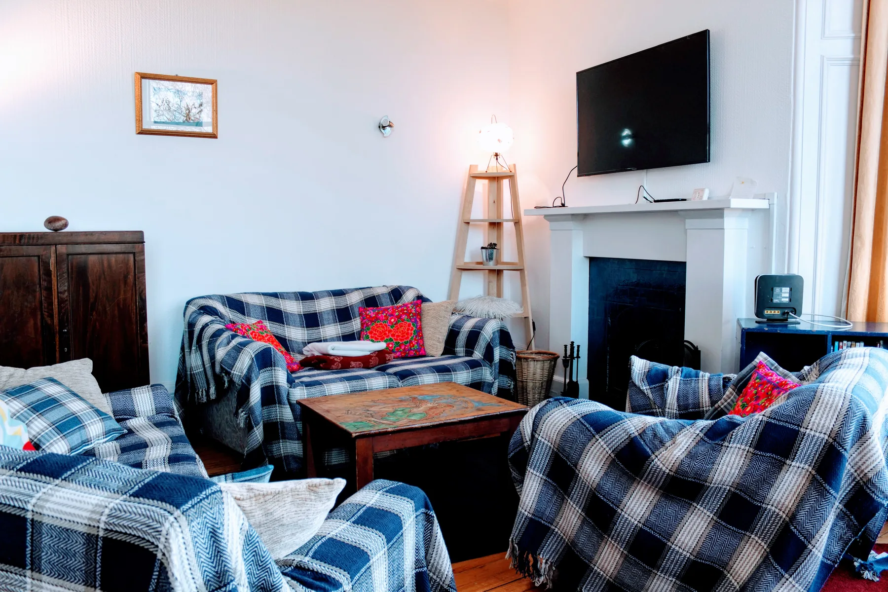 Una sala de estar con asientos a cuadros, una mesa de centro y una chimenea.