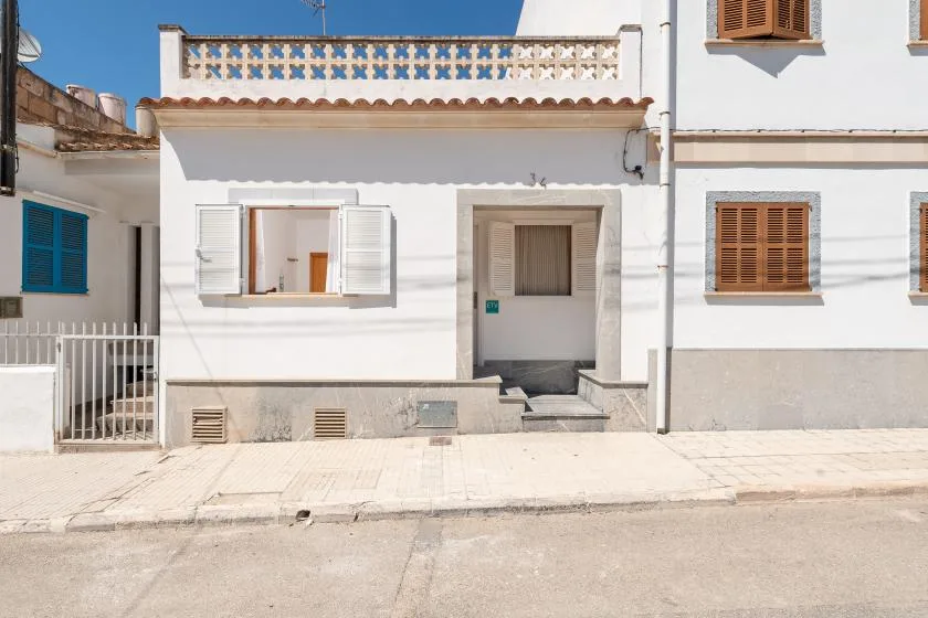 A white building facade with an open window and a recessed entrance.