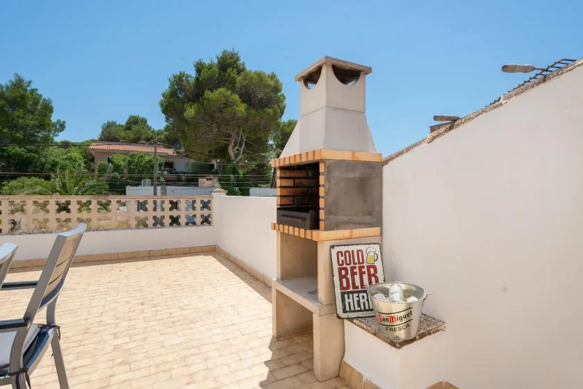 A sunny outdoor terrace features a built-in barbecue and open paved space.