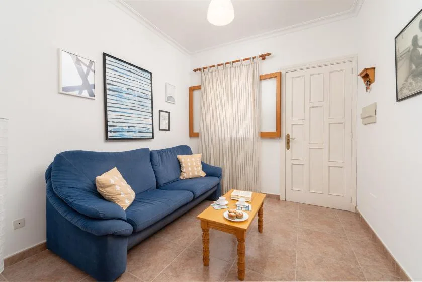 A living room with blue seating, framed wall art, and a small coffee table.