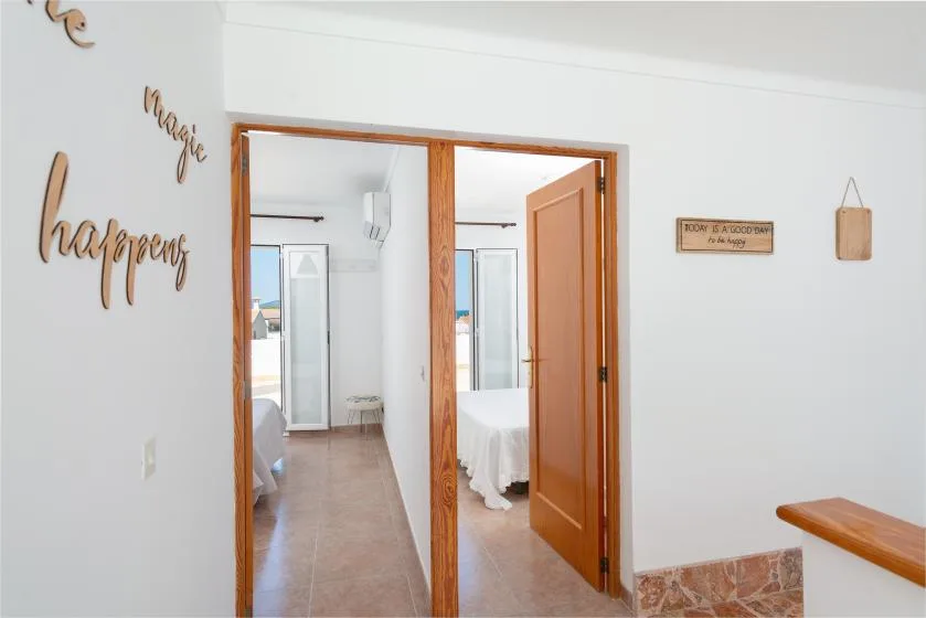 A bright interior hallway opens into bedrooms through wooden doorways.